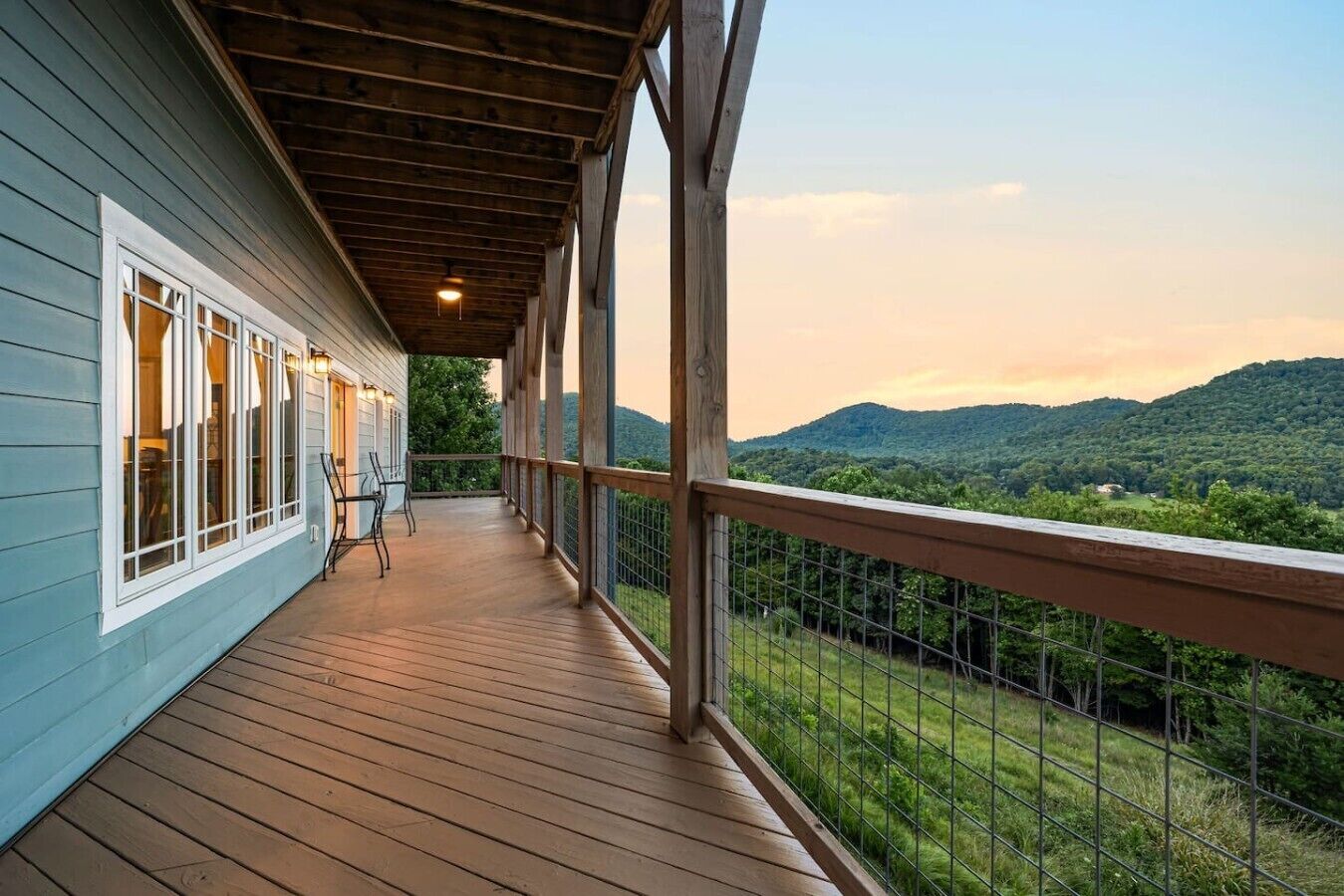 Eine überdachte Holzterrasse mit Geländer, mit Blick auf eine gebirgige Landschaft.
