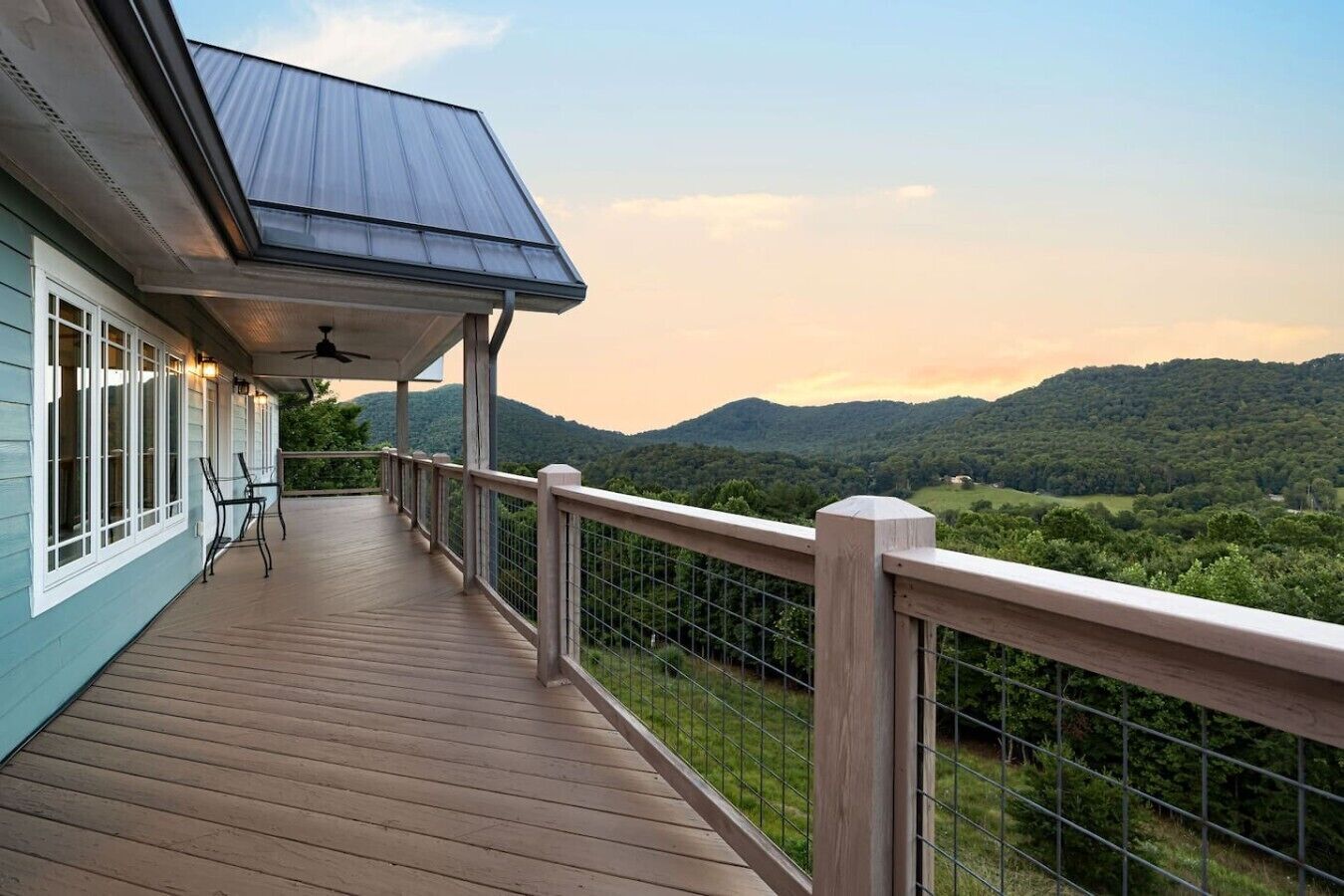 Eine Holzterrasse mit Metallgeländer, mit Blick auf eine bewaldete Landschaft.