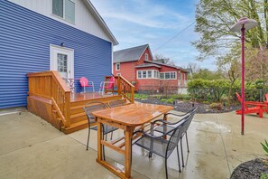 A wooden deck with a table and chairs, a red slide, and a house with a blue exterior. - Ludington Home w/ 6 Bicycles < 1 Mi to Beach! (Ludington)