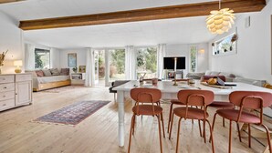 A spacious living area with a dining table, multiple chairs, a sofa, and a television.