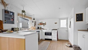 A modern kitchen with white cabinets, a built-in oven, and a wooden floor.