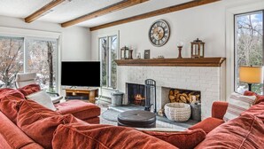 Een gezellige woonkamer met een open haard, een groot raam en een televisie.