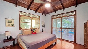 A room with a bed, wooden ceiling, large windows, and a view of the outside. - Casa & Casita Miel - 3 Bed Jungle Oasis W/ Pool (Puerto Viejo de Talamanca)