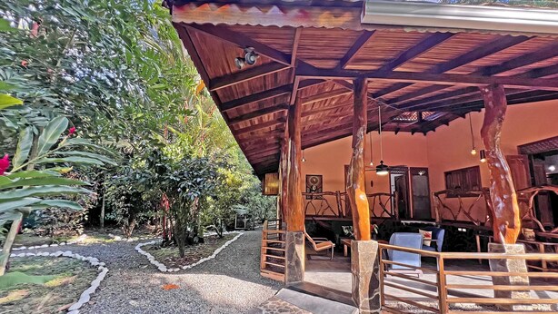 A covered outdoor seating area with a wooden structure, stone flooring, and surrounding greenery. - Casa & Casita Miel - 3 Bed Jungle Oasis W/ Pool (Puerto Viejo de Talamanca)