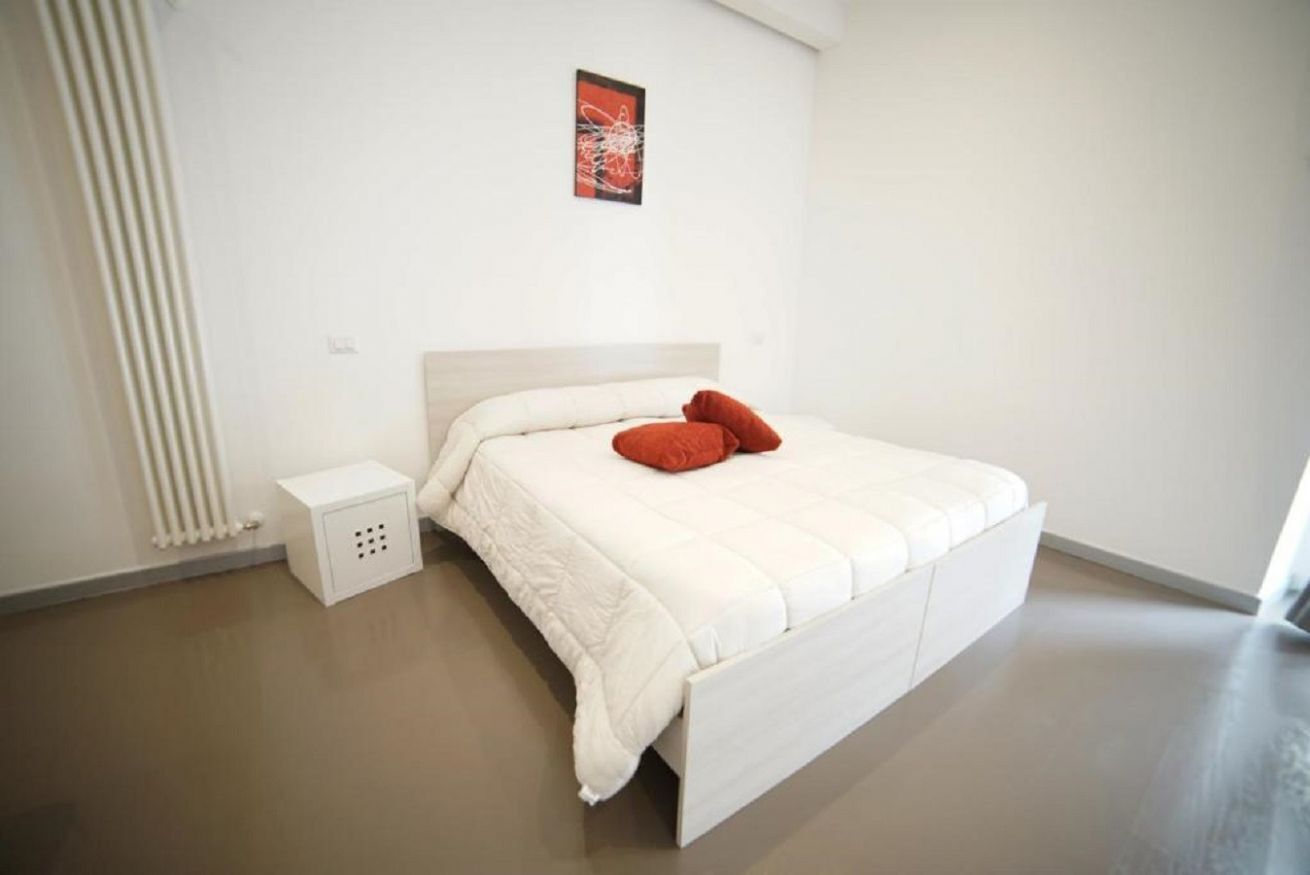 Un dormitorio minimalista con una cama, una mesita de noche y un radiador.