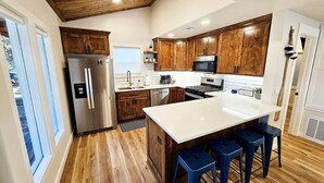 Una cocina moderna con armarios de madera, electrodomésticos de acero inoxidable y una isla central con taburetes de bar.