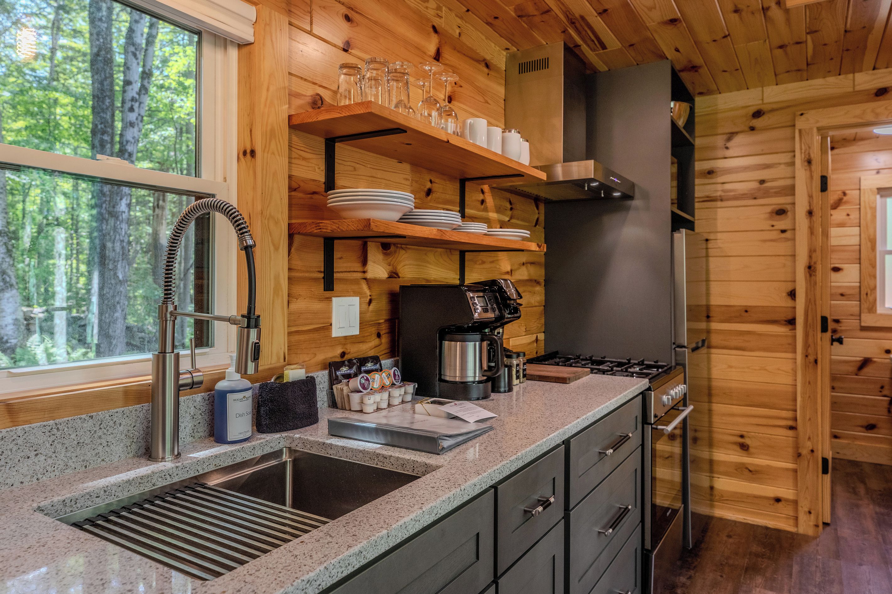 A kitchen with wooden walls, a stainless steel sink, and a coffee machine.
