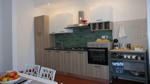 Eine moderne Küche mit Holzausstattung, einem Gasherd, einem Backofen und einem kleinen Essbereich mit Tisch und Stühlen.