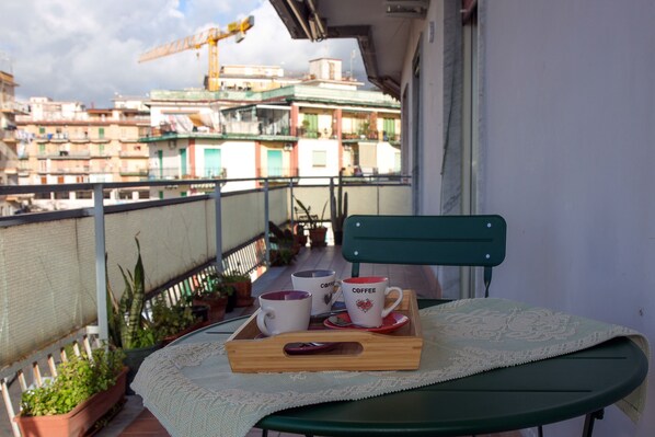 Ein Balkon mit einem für zwei Personen gedeckten Tisch, zwei Kaffeetassen und einer Ablagefläche.