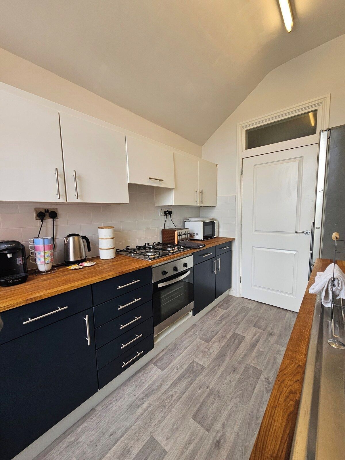 A compact kitchen with white cabinets, a microwave, a stove, and a coffee maker.