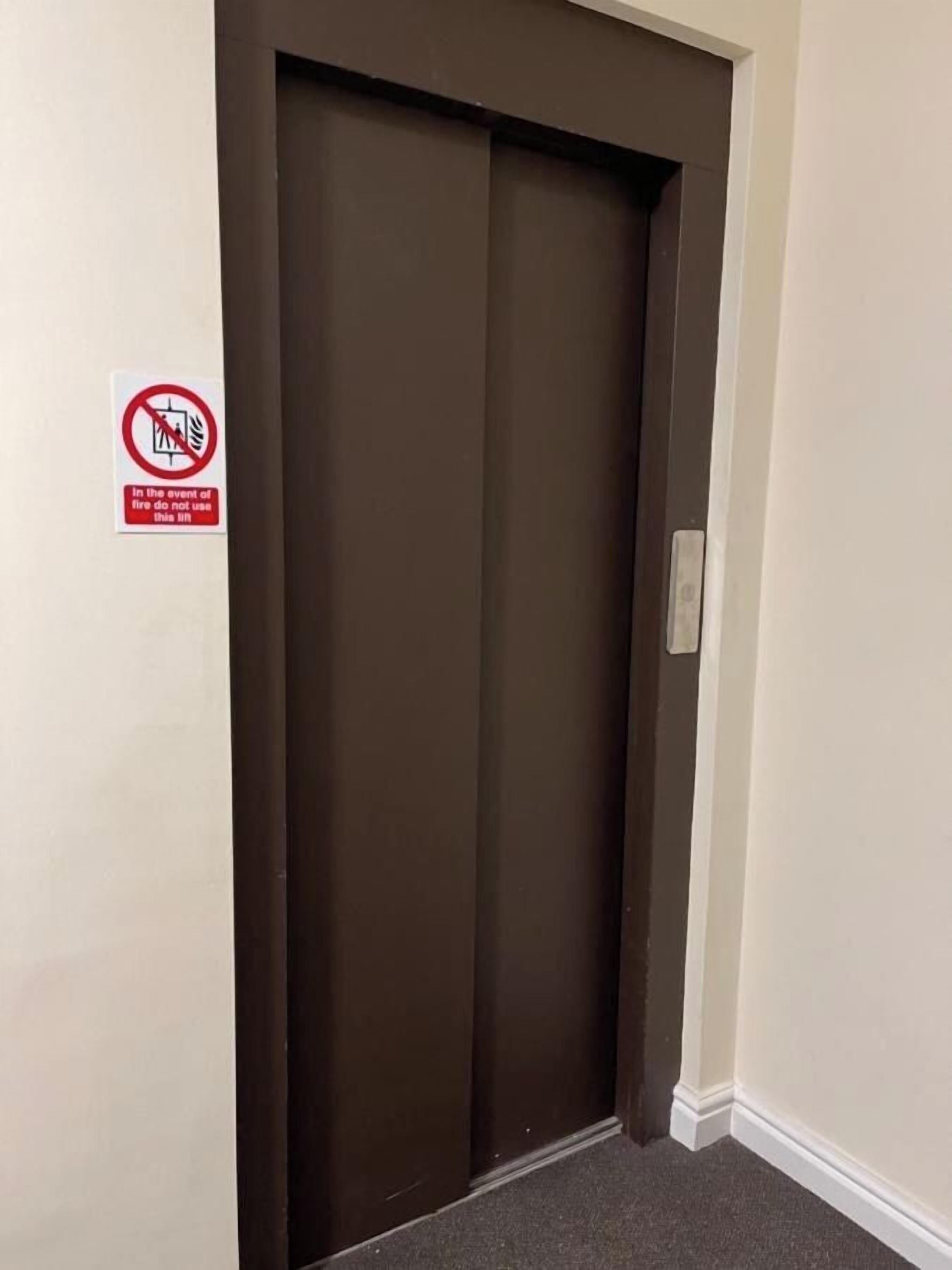 A closed elevator door with a no-smoking sign on the wall beside it.