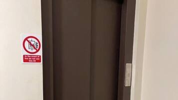 A closed elevator door with a no-smoking sign on the wall beside it.