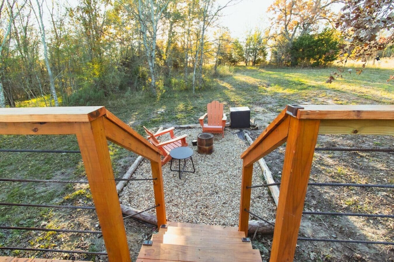 Eine Holterrasse mit Blick auf eine bewaldete Landschaft, Sitzgelegenheiten im Freien und einer Feuerstelle.