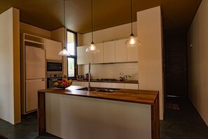 Una cocina moderna con una isla central, luces colgantes y vistas al área de estar contigua.