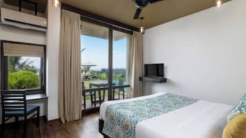 Een hotelkamer met een bed, een bureau, een stoel, een televisie en een balkon met uitzicht.