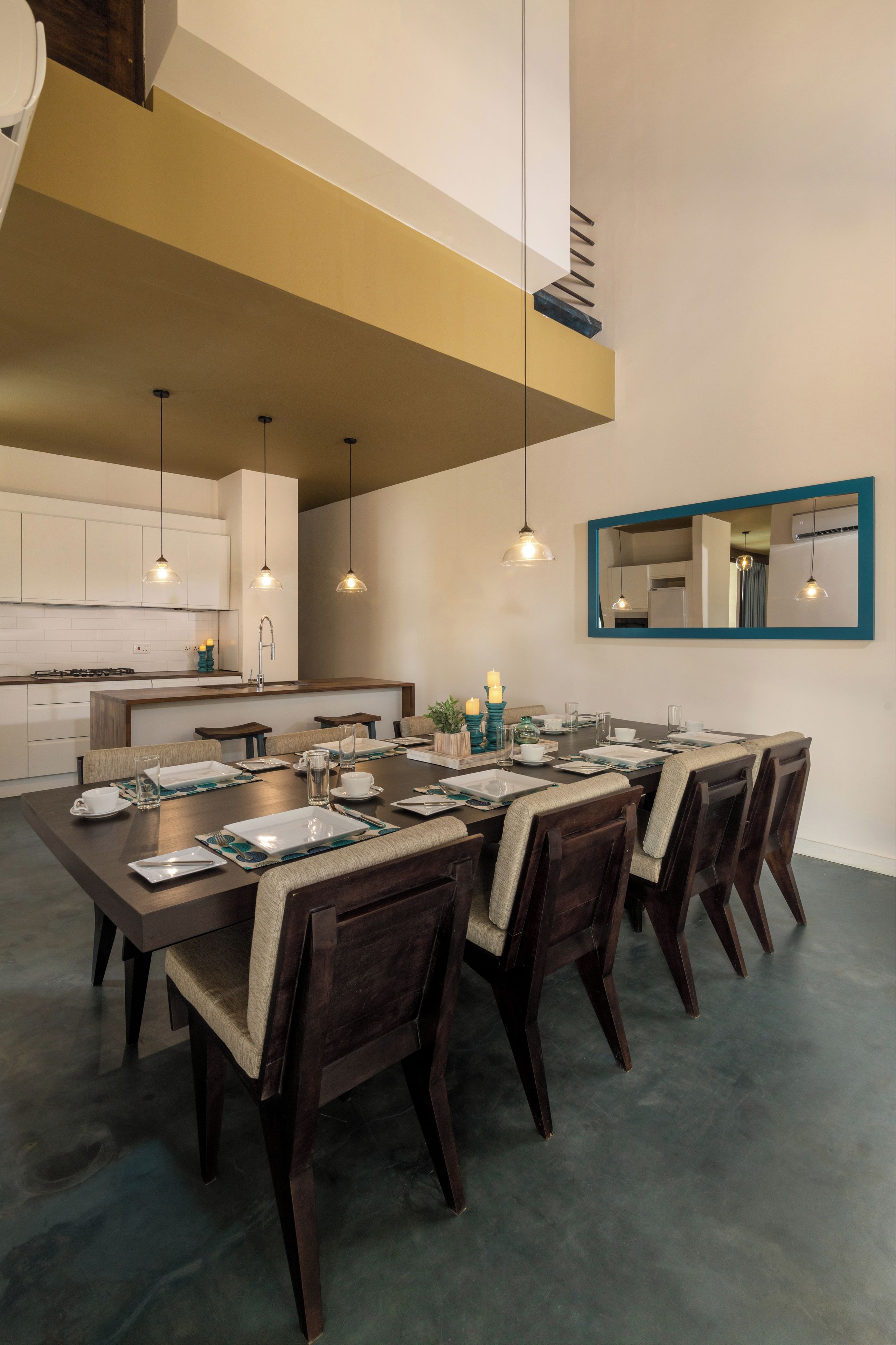 A modern dining area with a long table, dark wooden chairs, and pendant lighting.