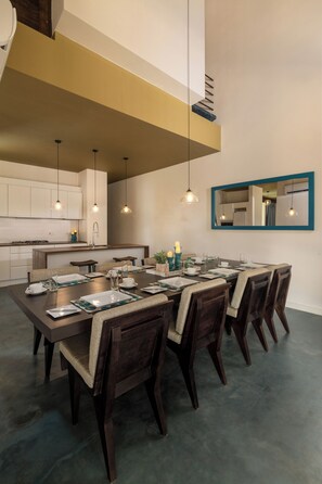 A modern dining area with a long table, dark wooden chairs, and pendant lighting. - Inidi Leisure Luxury Villas (Wadduwa)