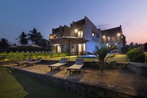 A modern two-story house with a swimming pool, outdoor seating, and a well-lit patio area. - Inidi Leisure Luxury Villas (Wadduwa)