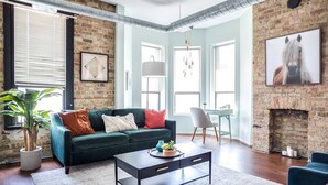 A living room with a green sofa, a coffee table, and a fireplace. - Luxury Downtown Penthouse with Private Rooftop! (Chicago)