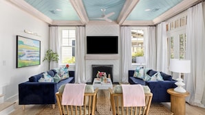 A living room with two dark blue sofas, a coffee table, and a fireplace. - Dual Primary Suites & Luxe Whimsical Interiors (Bluffton)