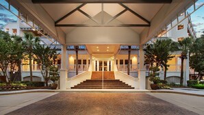 Entrada de hotel con una escalera monumental, un paseo techado y vistas de los edificios circundantes.