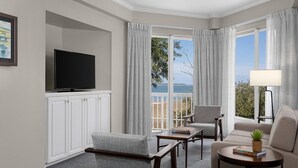 Habitación de hotel con televisión de pantalla plana, un sofá, una silla, una mesita y vistas al exterior.