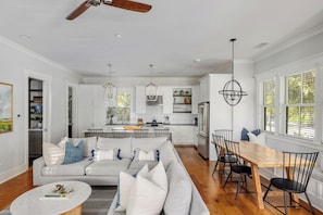 A spacious living room with a sofa, coffee table, and dining area with chairs.