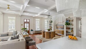 A spacious living area with a large sofa, a dining table, and a kitchen area with white cabinetry and a marble countertop. - Luxe Retreat with Carriage House & Water Views (Bluffton)