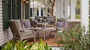 A porch with outdoor furniture, a table with drinks, and a view of the surrounding trees. - Luxe Retreat with Carriage House & Water Views (Bluffton)
