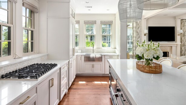 A modern kitchen with white cabinetry, a stainless steel stove, and a large window. - Luxe Retreat with Carriage House & Water Views (Bluffton)