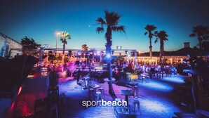 An outdoor venue with tables and chairs, palm trees, and a stage for performances. - T2 Prado Plage / Vélodrome (Marseille)