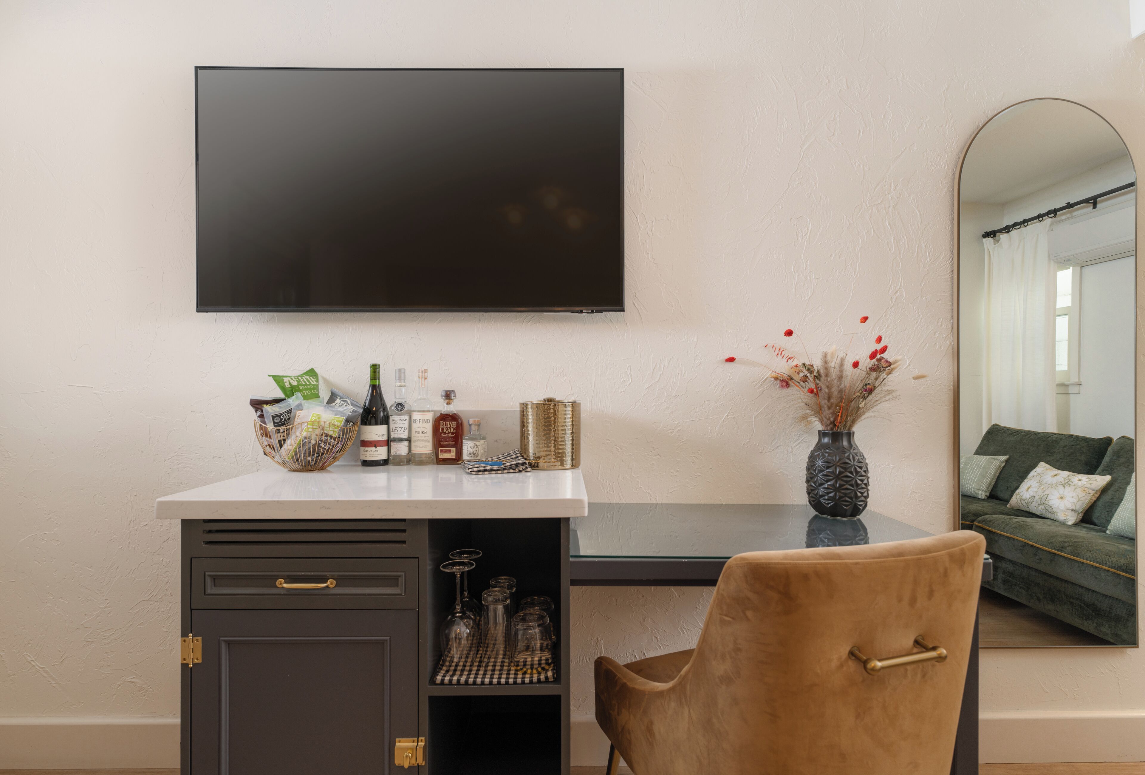 Un saló modern amb un televisor de pantalla plana fixat a la paret, una taula de centre amb un ram de flors i una zona d'estar còmoda amb un sofà i una cadira.