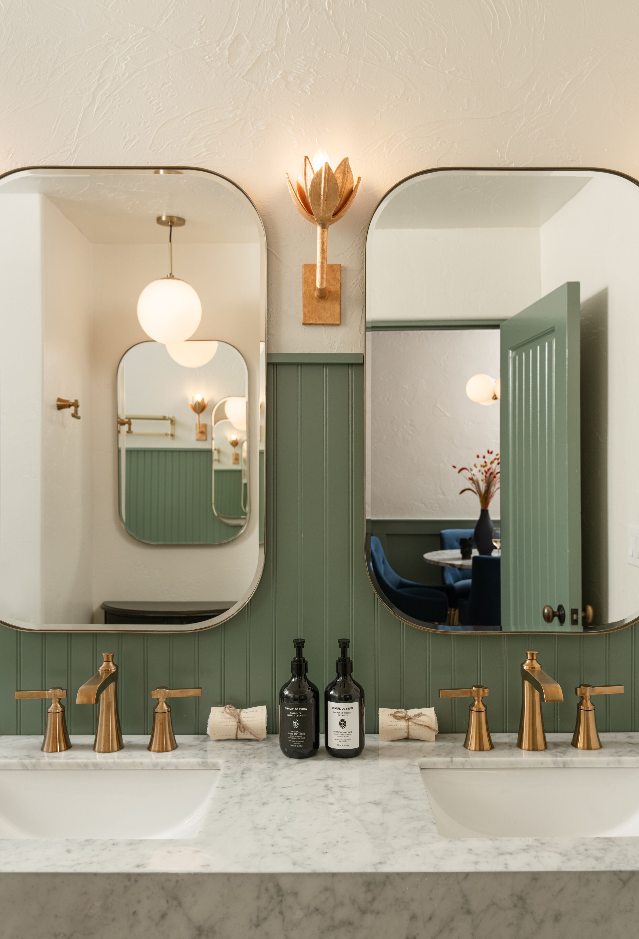 A bathroom with two sinks, a mirror, and a wall-mounted light fixture.