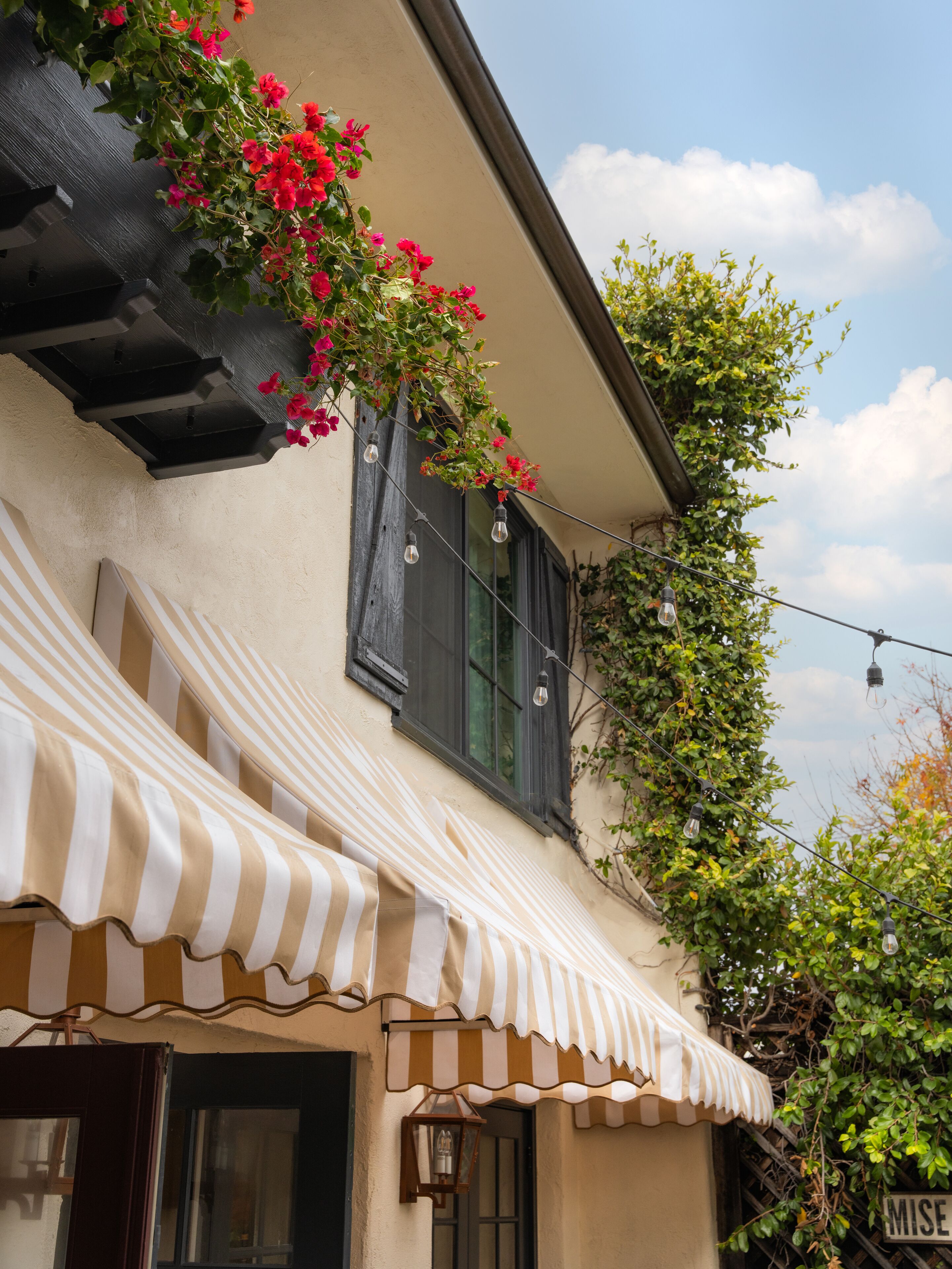 A building with a striped awning, a window with a shutter, and a sign that reads "MISE". - Petit Soleil (San Luis Obispo)