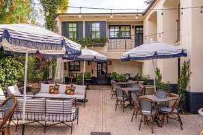 Un patio al aire libre con sombrillas a rayas, muebles de mimbre y plantas en macetas.
