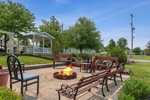 An outdoor patio with a fire pit, wooden benches, and chairs. - Room 7- Sunset Acres Motel (Hudson)