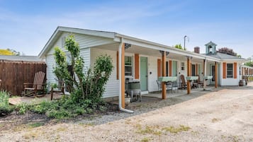 A single-story motel with a covered porch, outdoor seating, and a small bell tower.