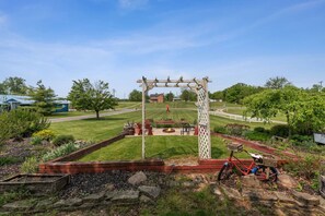 Ein Garten mit einer Holz-Pergola, einer Feuerstelle und einem Fahrrad.