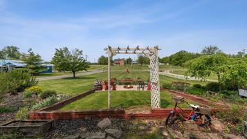 A garden with a wooden pergola, a fire pit, and a bicycle.