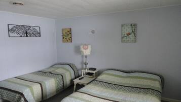 A room with two single beds, a nightstand with a lamp, and wall art.