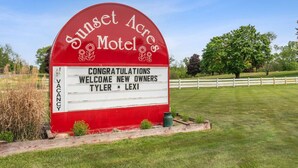 A red and white sign for Sunset Acres Motel with a message welcoming new owners Tyler and Lexi. - Sunset Acres Motel - Room 1 (Hudson)