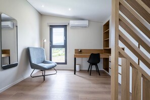Una camera moderna con una scrivania, due sedie, uno specchio e una scala.
