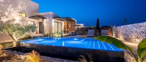 A modern outdoor pool area with a stone wall and minimalist architecture.