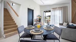 A modern living room with a dining area, a staircase, and a view of the outdoors. - Campo Premium Villa with Private Pool (Kos)
