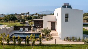A modern house with a swimming pool, outdoor seating, and a view of the sea. - Campo Premium Villa with Private Pool (Kos)