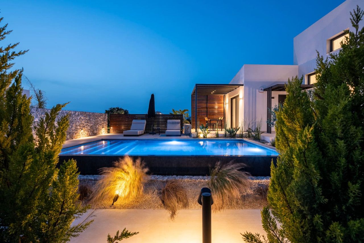 Un espace piscine extérieur moderne, agrémenté d’un mur en pierre, d’une terrasse en bois et de chaises longues.
