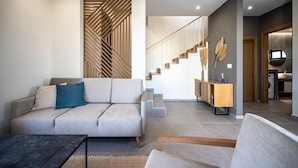 Una sala de estar moderna con un sofá, una mesa de centro y una escalera que lleva a una zona de cocina.