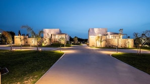Una zona residencial moderna con dos casas, un camino pavimentado y jardines bien cuidados.