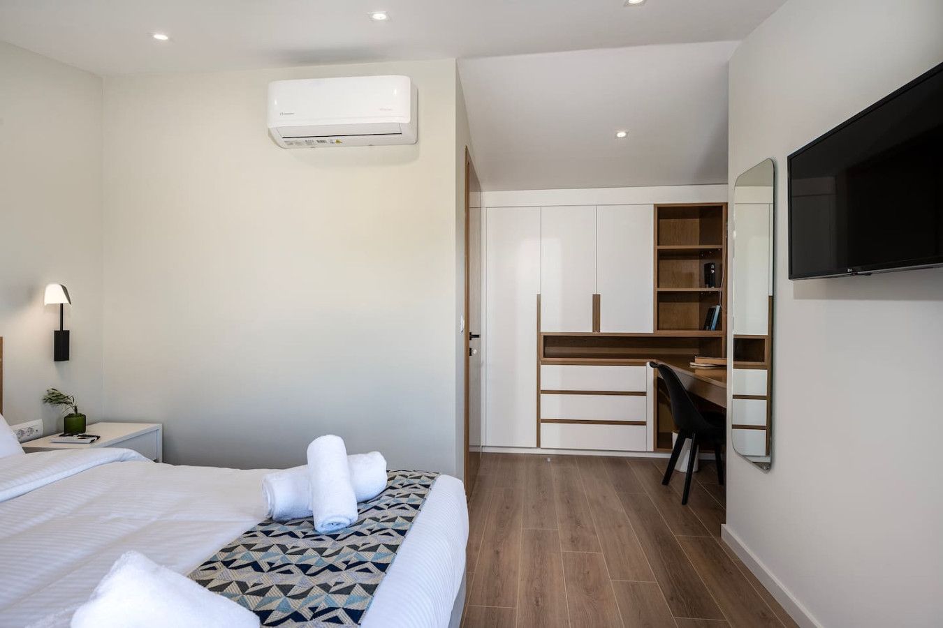 A modern hotel room with a bed, a desk, and a TV.