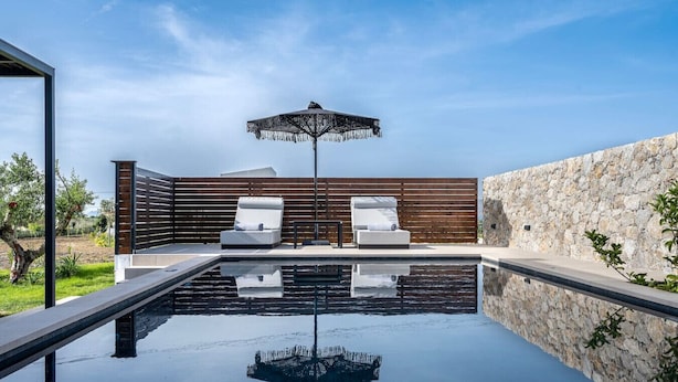 Una piscina al aire libre con dos sillas de descanso y una sombrilla.
